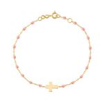 The Little Gigi Classic Cross Charm Bracelet by Gigi Clozeau is an elegant piece featuring 18-carat gold accents, pink beads, and the Classic Gigi Cross Charm delicately strung alongside resin pearls.