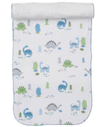 The Kissy Kissy Dinosaur Era Burp Cloth is a white Pima cotton cloth with blue trim featuring blue and green cartoon dinosaurs, trees, and bushes—ideal for baby boys. One end of the burp cloth is rolled up.