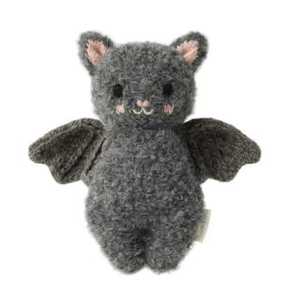 The Baby Bat - Charcoal by Cuddle + Kind is a handcrafted gray plush bat toy made from soft cotton, featuring a textured body, black wings, small ears, a smiling face, and light pink accents on the cheeks—an ideal soft companion for babies—shown against a white background.