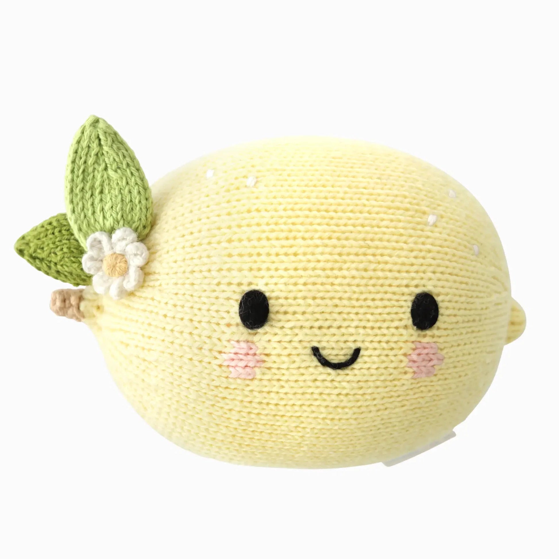The Cuddle + Kind Baby Lemon is a lovingly handcrafted, knitted plush toy made from Peruvian cotton. Shaped like a lemon with a smiling face, pink cheeks, green leaves, and a white flower attached, this soft baby toy offers heirloom-quality charm.