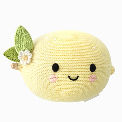 The Cuddle + Kind Baby Lemon is a lovingly handcrafted, knitted plush toy made from Peruvian cotton. Shaped like a lemon with a smiling face, pink cheeks, green leaves, and a white flower attached, this soft baby toy offers heirloom-quality charm.