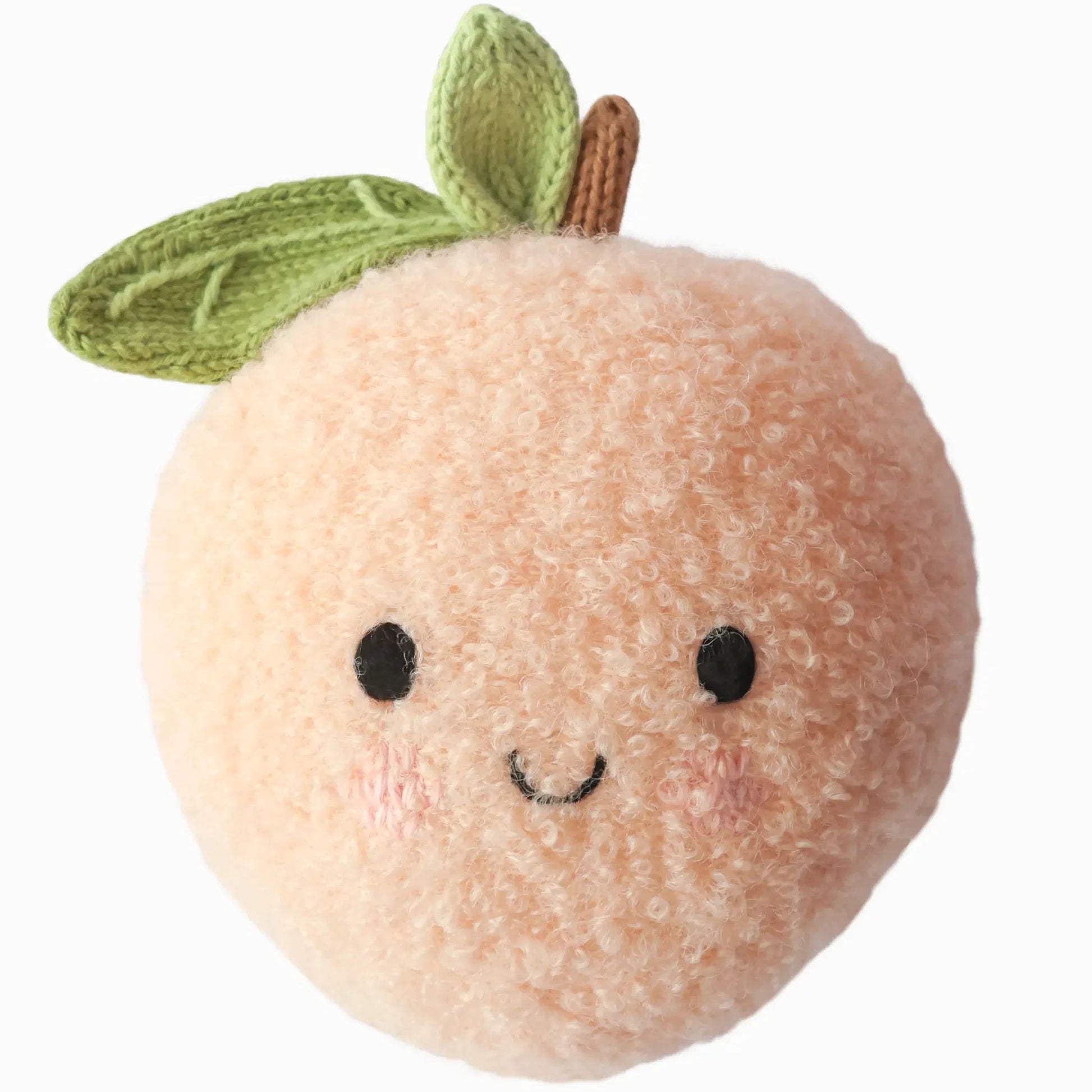 Introducing Baby Peach by Cuddle + Kind—a handcrafted plush peach toy made from soft Peruvian cotton yarn, featuring a cheerful smiling face, black eyes, pink cheeks, and two green knit leaves on top. This heirloom-quality baby animal is irresistibly cuddly and full of charming details.