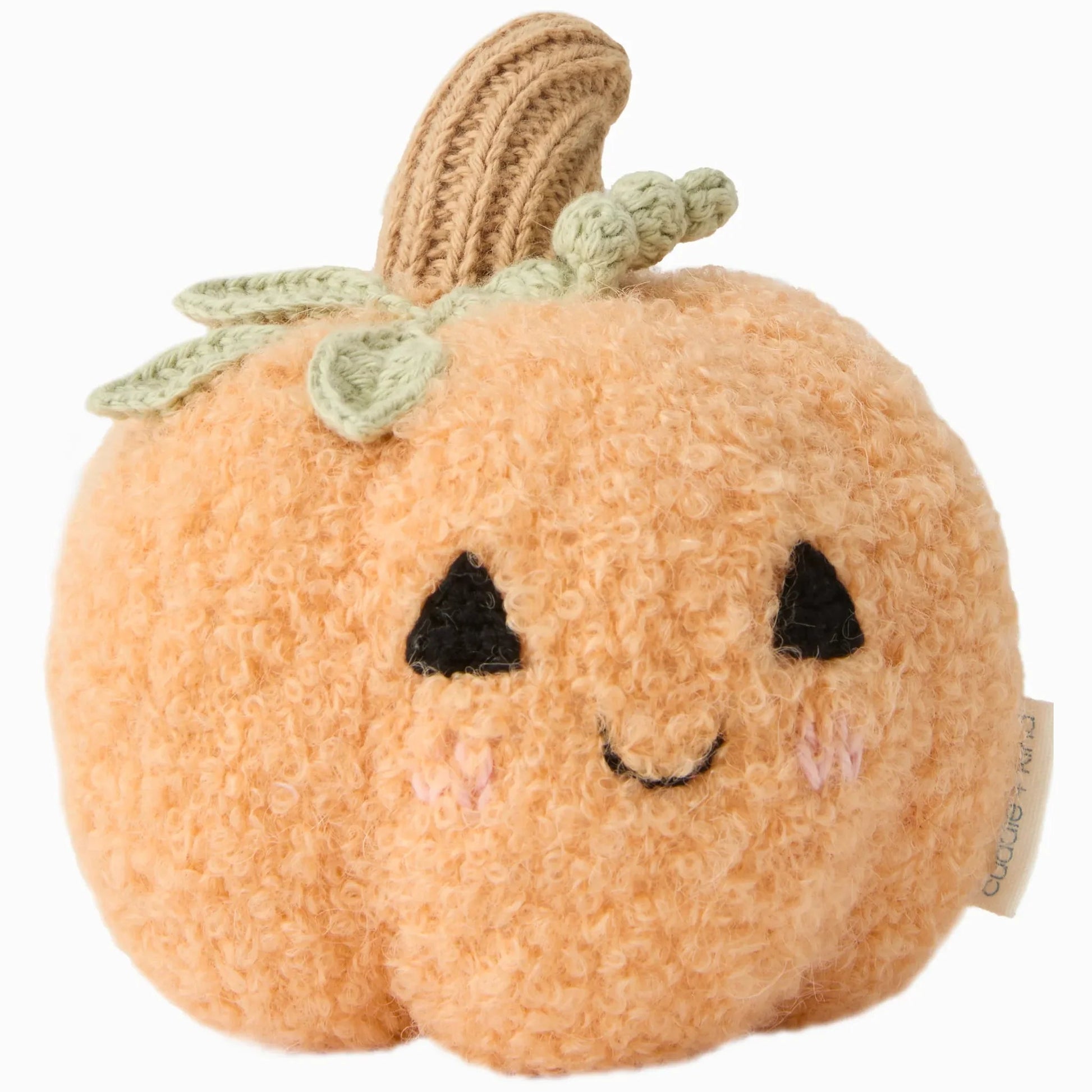 The Cuddle + Kind Baby Pumpkin is a plush toy handcrafted from cotton yarn, featuring a textured orange body, green crochet leaves, a brown stem, and a smiling face with black eyes and blushing cheeks—making it the perfect soft baby companion or charming heirloom baby pumpkin.