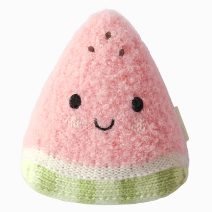The Cuddle + Kind Baby Watermelon is a handcrafted cotton plush toy shaped like a smiling pink watermelon slice, complete with black eyes and brown seed details on a white background—a soft and delightful companion for little ones.