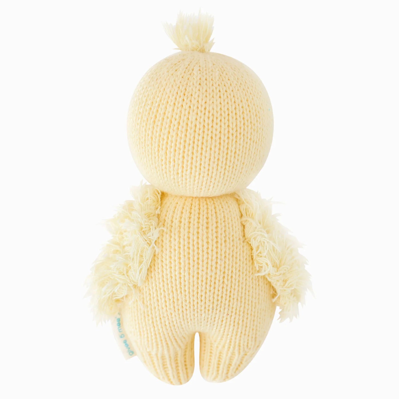 The Baby Duckling by Cuddle + Kind is a knitted yellow plush toy resembling a chick, shown from the back, featuring textured wings and a small tuft on its head. Lovingly handcrafted from soft Peruvian cotton yarn, this charming piece is one of our artisanal cotton toys.