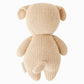 The Cuddle + Kind “Baby Puppy” is a handcrafted beige cotton plush toy shaped like a dog, shown from the back with floppy ears, a short tail, and a tag on its side. Designed to be a soft baby companion, it’s perfect for cuddles and gentle play.