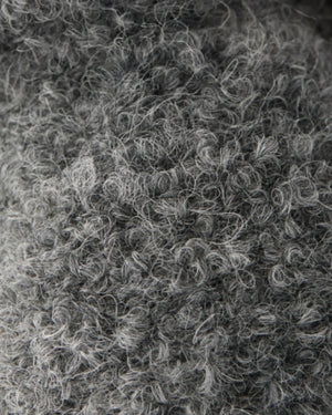 Close-up of a textured gray wool fabric with tight curls and loops, showing detailed fibers and a soft, fuzzy appearance—just like the gentle finish found on the Baby Bat - Charcoal by Cuddle + Kind.