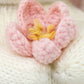 Close-up of Cuddle + Kind’s Baby Bunny - Blooming Tulip, featuring a pink and yellow crocheted flower handcrafted from heirloom-quality Peruvian cotton, displayed on a white knitted background.