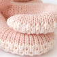 Close-up of two Baby Octopus - Soft Coral Pink booties by Cuddle + Kind, stacked together on a white background, lovingly crafted from premium Peruvian cotton yarn.
