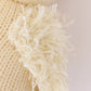 Close-up of cream-colored knitted fabric made from soft Peruvian cotton yarn, with a fluffy fringe along the edge, highlighting the detailed texture of Cuddle + Kind’s Baby Duckling—perfect for heirloom baby animals or handcrafted cotton toys.