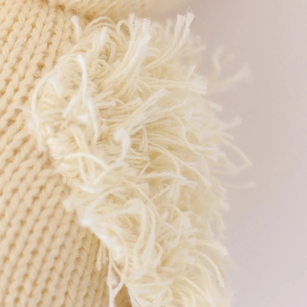 Close-up of cream-colored knitted fabric made from soft Peruvian cotton yarn, with a fluffy fringe along the edge, highlighting the detailed texture of Cuddle + Kind’s Baby Duckling—perfect for heirloom baby animals or handcrafted cotton toys.
