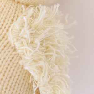 Close-up of cream-colored knitted fabric made from soft Peruvian cotton yarn, with a fluffy fringe along the edge, highlighting the detailed texture of Cuddle + Kind’s Baby Duckling—perfect for heirloom baby animals or handcrafted cotton toys.