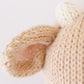 Close-up of a knitted stuffed animal’s ear made from handcrafted cotton yarn in beige and white, showing detailed stitching and texture—a Baby Cow soft toy by Cuddle + Kind.