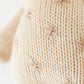 Close-up of Baby Giraffe by Cuddle + Kind: a beige, heirloom-quality knit accented with small star-shaped light brown stitches, crafted from luxurious Peruvian cotton yarn.