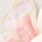 Close-up of Cuddle + Kind’s Baby Butterfly - Petal Pink: an heirloom-quality, hand-knit fabric shaped like a flower petal in soft pink and cream tones—ideal for collectible creations or hand-knit baby decor.
