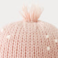Close-up of the top of the Baby Octopus - Soft Coral Pink hat by Cuddle + Kind, crafted from soft Peruvian cotton yarn in a gentle pink hue, featuring charming white dots and a small tuft of yarn at the crown against a plain background.