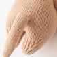 Close-up of a knitted object resembling the back and tail of a small animal, lovingly crafted in beige yarn from handcrafted Peruvian cotton to create Cuddle + Kind’s heirloom-quality Baby Otter.