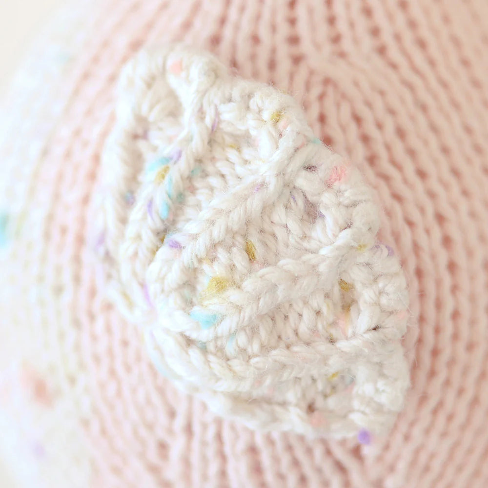 Close-up of Cuddle + Kind’s Baby Seahorse in Powder Pink, showcasing its heirloom-quality Peruvian cotton knit and a white leaf-shaped accent with pastel flecks.