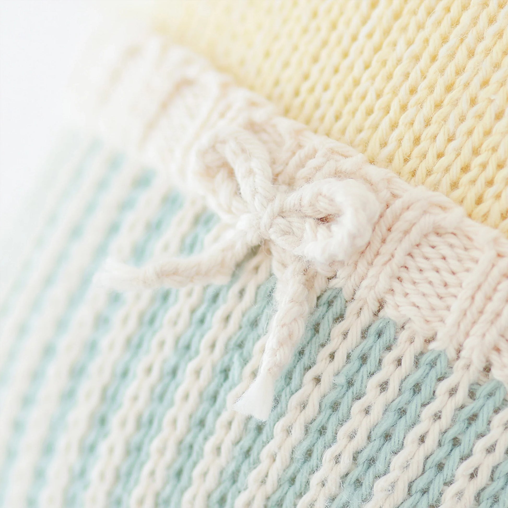Close-up of Finley the Duckling - Regular 20" by Cuddle + Kind, showing pastel yellow, blue, and cream knitted fabric with a small cream bow—ideal for crafting a cuddly plush toy or a sweet birthday gift.