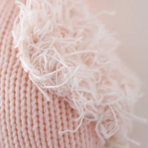 Close-up of Baby Flamingo by Cuddle + Kind, featuring pink knitted Peruvian cotton yarn and a fringe of loose, fluffy threads along the edge.