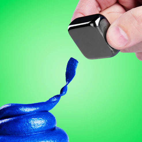 A hand holds a black magnet above a swirl of Crazy Aarons Tidal Wave Magnetic Storm Thinking Putty, a captivating sensory toy, set against a bright green background.