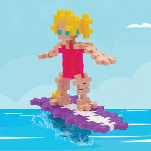 The Plus Plus Tube - Surfer Girl features a block-style toy figure with yellow hair and a pink swimsuit on a purple and white surfboard, inspiring creative play and building fine motor skills for kids.