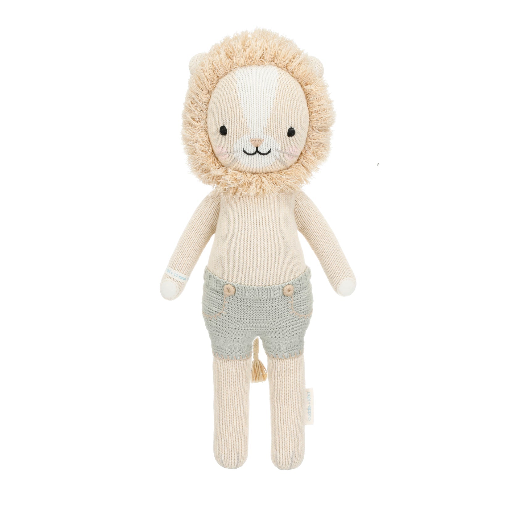 Sawyer the Lion - Little 13" by Cuddle + Kind is a knitted plush toy featuring a beige body, fluffy mane, embroidered face, and light gray shorts—beautifully crafted to inspire courage and kindness in every hug, shown against a white background.