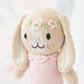 Tiny Hannah the Bunny Blush by Cuddle + Kind is an artisan-made, fair trade hand-knit bunny doll with long floppy ears, black eyes, floral accents on its head, and a pale pink sweater.