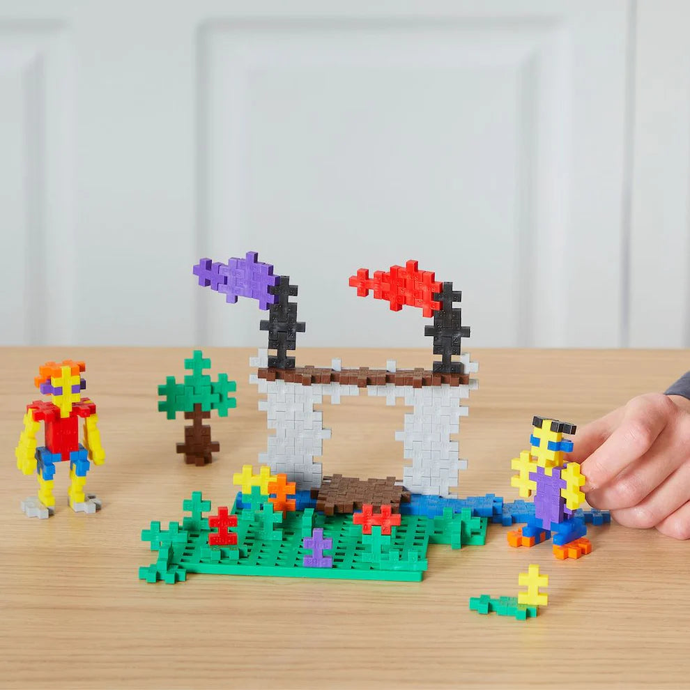 Plus Plus Tube - 240 Piece Basic Mix features colorful interlocking blocks for building figures, a tree, and a bridge on a wooden surface, fostering creative play and fine motor skills as kids adjust their creations.