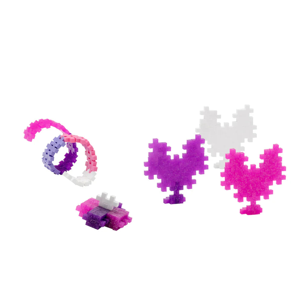 The Plus Plus Tube - 240 Piece - Glitter Mix features colorful interlocking pieces in purple, pink, and white that can be assembled into rings and heart shapes, inspiring creative play and enhancing fine motor skills.