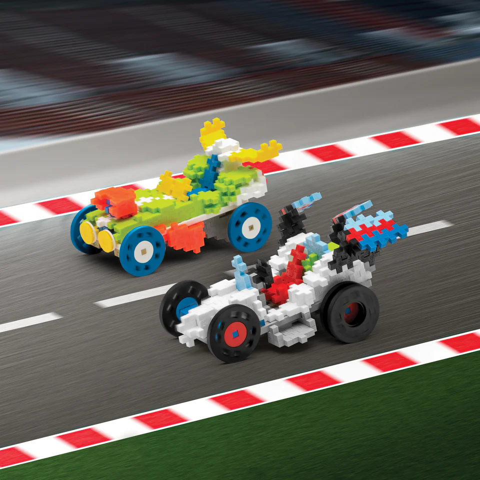 Two colorful toy race cars built from Plus Plus Learn to Build - Vehicles interlocking bricks are shown on a racetrack with a red and white curb.