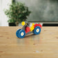 A Plus Plus Learn to Build - Vehicles STEM toy motorcycle, made of colorful interlocking plastic blocks, is displayed on a wooden table with a blurred plant in the background.