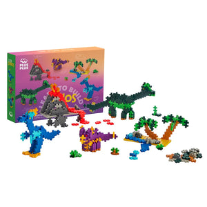 The Plus Plus Learn To Build - Dinosaurs set features pixel-style dinosaurs, plants, a volcano, fun accessories, and includes an illustrated guidebook for creative building—all displayed before the packaging.