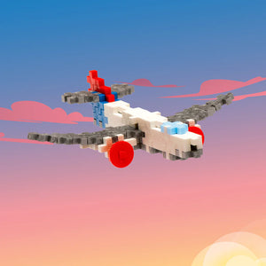 The Plus-Plus Tube - Airplane features interlocking blocks in white, gray, red, and blue, shown flying against a vibrant sunset sky—sparking creativity and imaginative STEM play for kids.