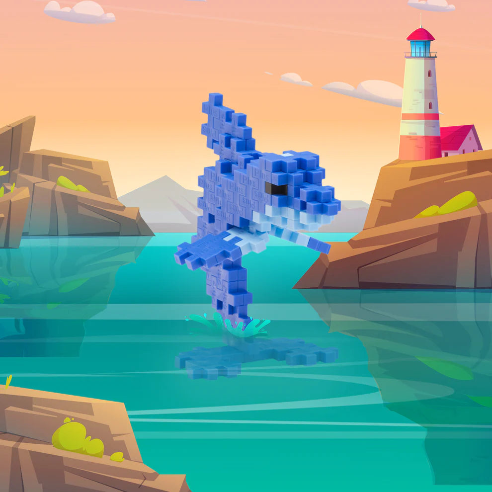 A pixelated blue dolphin leaps between rocky cliffs, built with the Plus Plus Tube - Dolphin set, while a lighthouse stands in the distance under a pink-orange sky—a perfect build for sea creature fans.