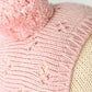 Close-up of the “My First Baby” pink hand-knit hat by Cuddle + Kind, featuring a pom-pom on top and a subtle star pattern, crafted from natural cotton and displayed on a mannequin head.
