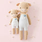 Asher the Cow by Cuddle + Kind comes in a regular 20" size, wearing white overalls with blue flowers. Set on a light pink background with white blooms, this plush cow inspires kindness and makes a sweet gift for any occasion.