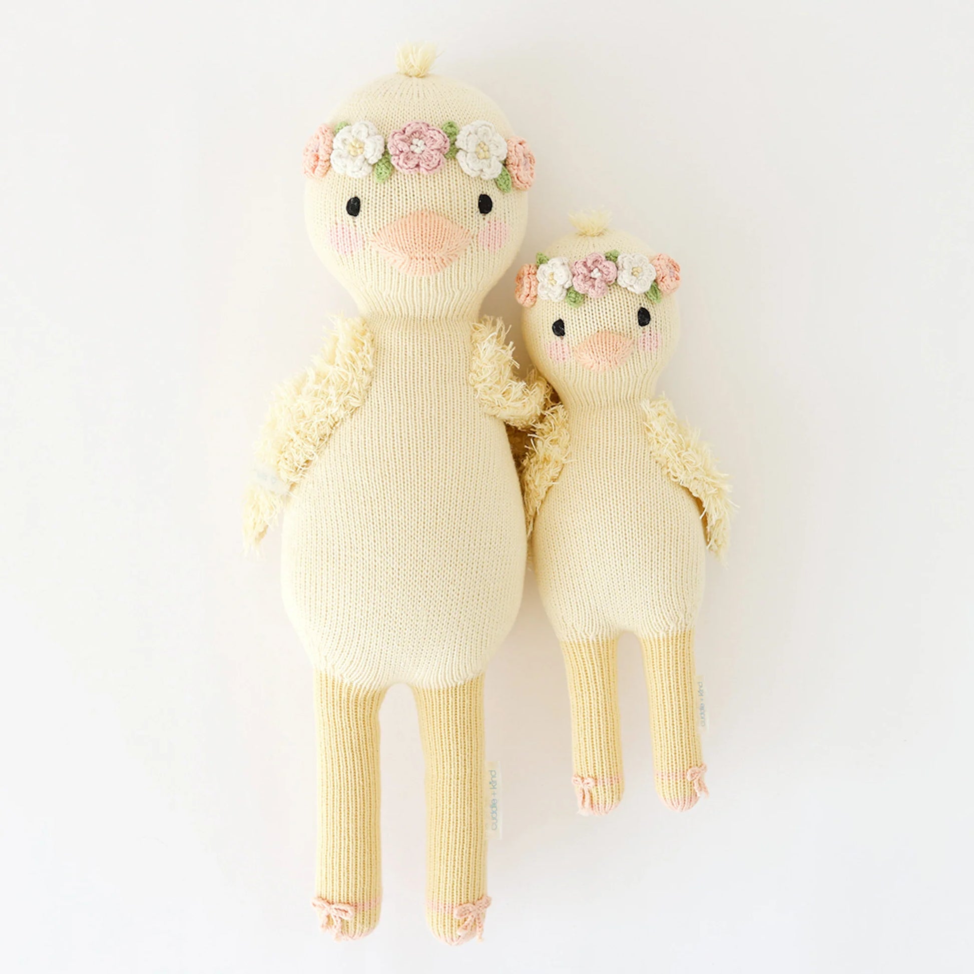 Cuddle + Kind’s Flora the Duckling Mauve plush toys, one large and one small, both with wildflower-inspired floral crowns, are placed side by side against a plain white background.