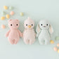 Cuddle + Kind’s hand-knit Baby Gosling, crafted from soft Peruvian cotton yarn, is displayed in a row with pastel eggs on a light background.