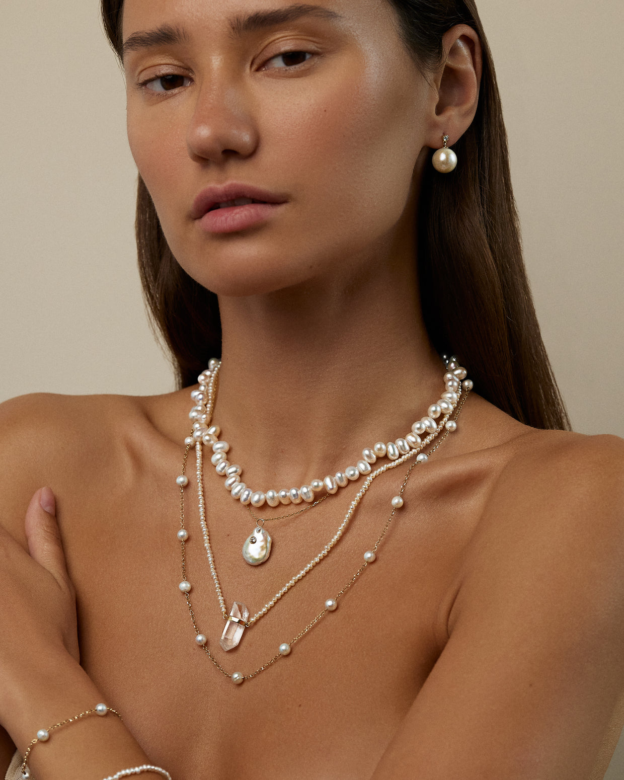 A woman wearing the Jia Jia Ocean Wild Pearl Necklace and a pearl earring poses against a plain background, with each piece meticulously handmade in NYC by the skilled artisans at Jia Jia.