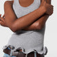 A person in the Stella McCartney Frilled Hem Rib Tank, blue jeans, and a brown belt stands with arms crossed.