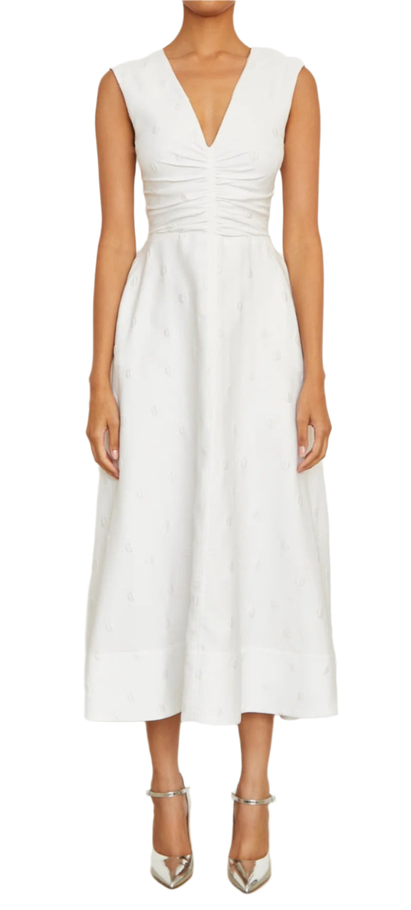 The person is wearing the exquisite Eliza Dress, a white Italian silk blend midi from Brandon Maxwell featuring a V-neck and bodice ruching, beautifully complemented by metallic pointed heels.