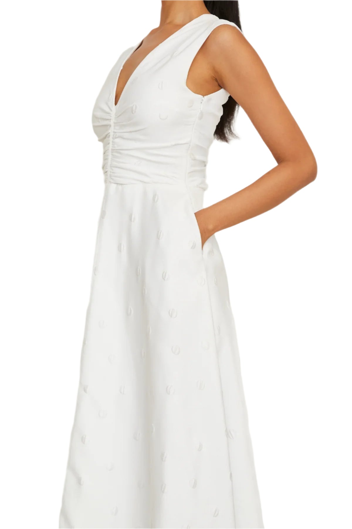 A woman wearing the Eliza Dress by Brandon Maxwell, a sleeveless white midi dress with a v-neckline and textured pattern, crafted from an Italian silk blend—an essential for the resort season.