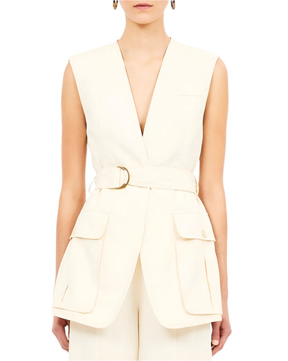 Someone is wearing the Ulla Johnson Twyla Vest, a sleeveless cream Tencel piece featuring a deep V-neck and large front pockets.