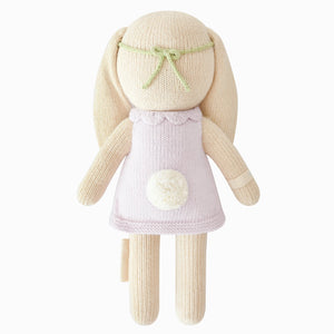 Hannah the Bunny Violet - Little 13" by Cuddle + Kind is a delightful knit bunny doll with long ears, dressed in a light purple dress and green headband, and finished with a white pompom tail. Set against a white background, this charming plush toy makes an ideal inspirational gift or birthday present for all ages.