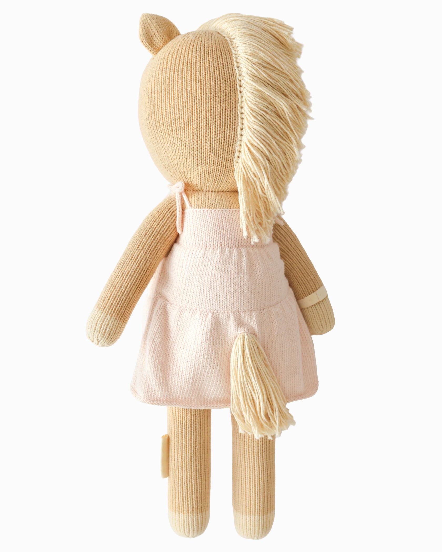 Kelsie the Pony by Cuddle + Kind—a regular 20" knitted horse plush toy with a cream mane and tail, dressed in a pale pink dress and shown from the back against a plain background—is perfect inspiration for creating a beautiful birthday gift.