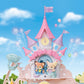 The Baby Dream Amusement Park by Calico Critters features a charming toy castle with pink towers and a clock, accompanied by two adorable animal figurines in front. Balloons and sparkles fill the blue sky background, making this enchanting playset feel like a magical amusement park adventure.