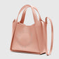 A blush pink Stella McCartney Logo Crossbody Tote Bag, made from vegan leather, features dual handles, a shoulder strap, and perforated branding on the front.