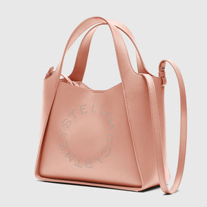 A blush pink Stella McCartney Logo Crossbody Tote Bag, made from vegan leather, features dual handles, a shoulder strap, and perforated branding on the front.