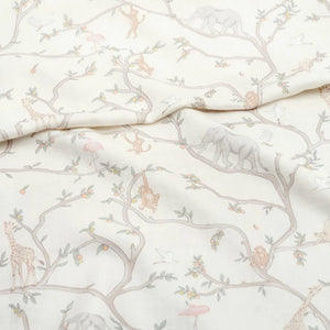 The Animal Parade Ivory Swaddle by Gooselings is a 100% cotton fabric featuring whimsical trees, elephants, giraffes, monkeys, and birds in muted colors—ideal for crafting a cozy swaddle blanket or adding charm to any nursery.